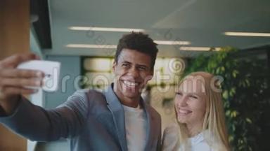 笑不同的同事在办公室<strong>自拍</strong>。快乐的黑人男子和笑着的金发女子<strong>一起自拍</strong>